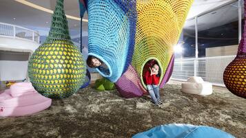 A modern interior with colorful, geometric hanging structures and soft seating areas.