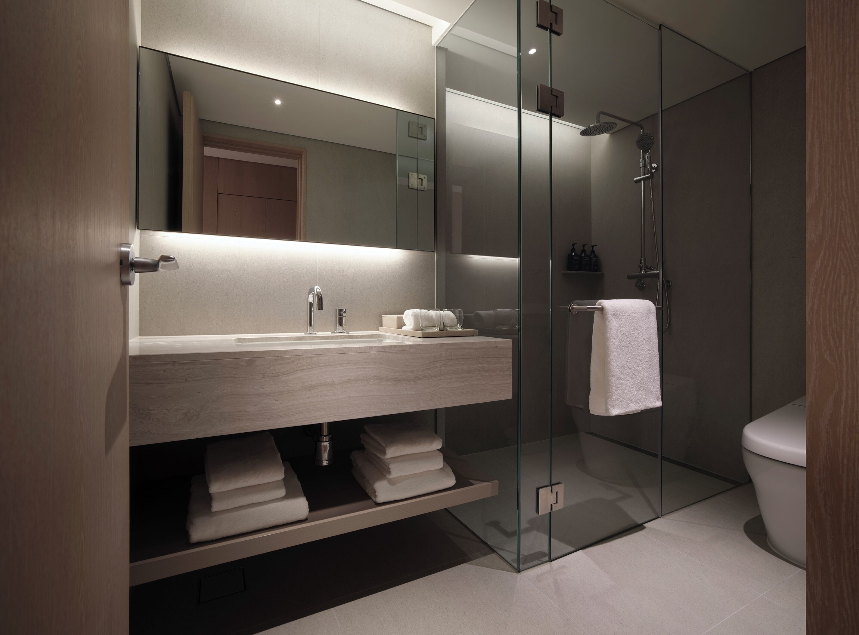 A modern bathroom with a glass-enclosed shower, a wooden vanity with a sink, and a mirror above the vanity.