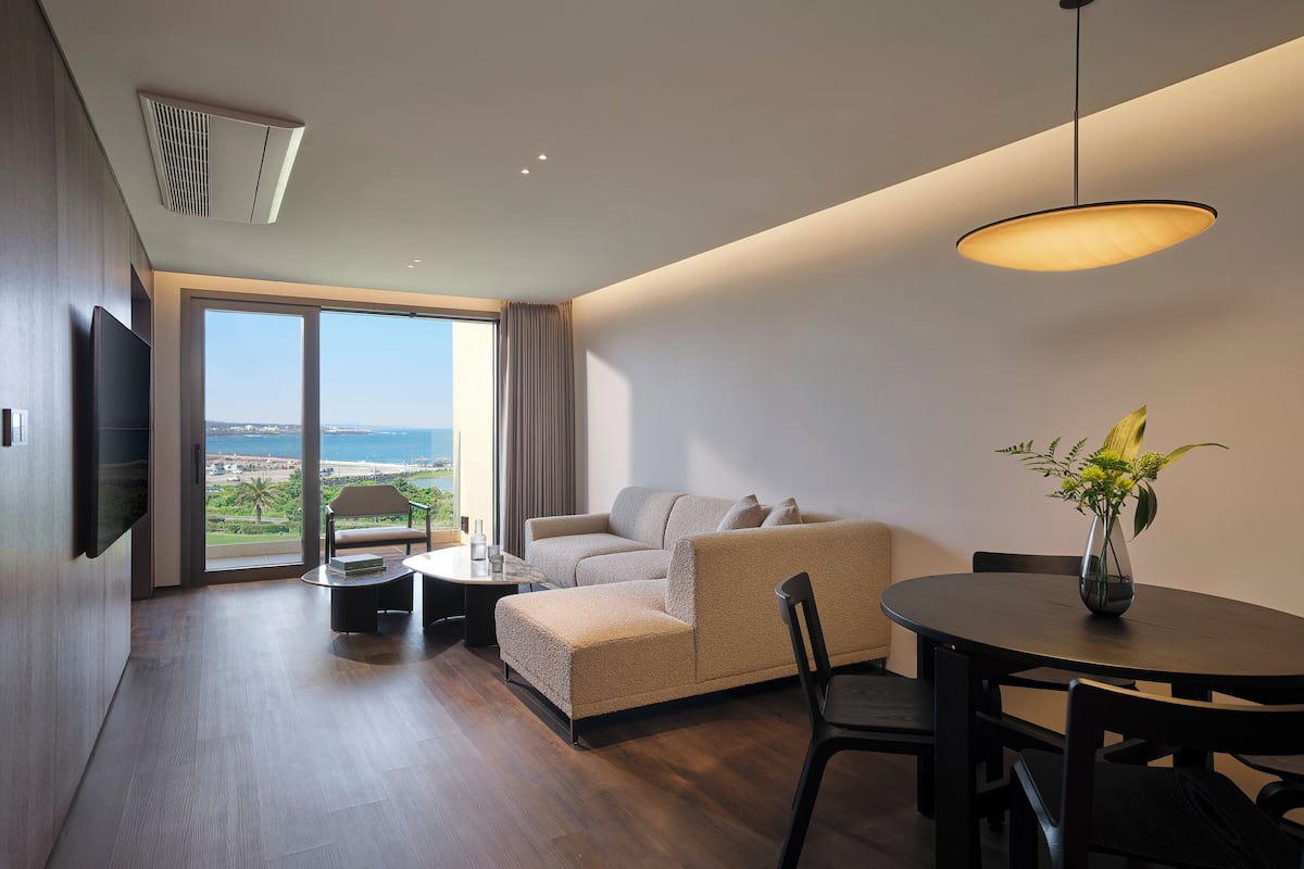 Un salon moderne avec un canapé, une table à manger et une vue sur l’extérieur.