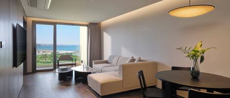 A modern living room with a sofa, a dining table, and a view of the outdoors.