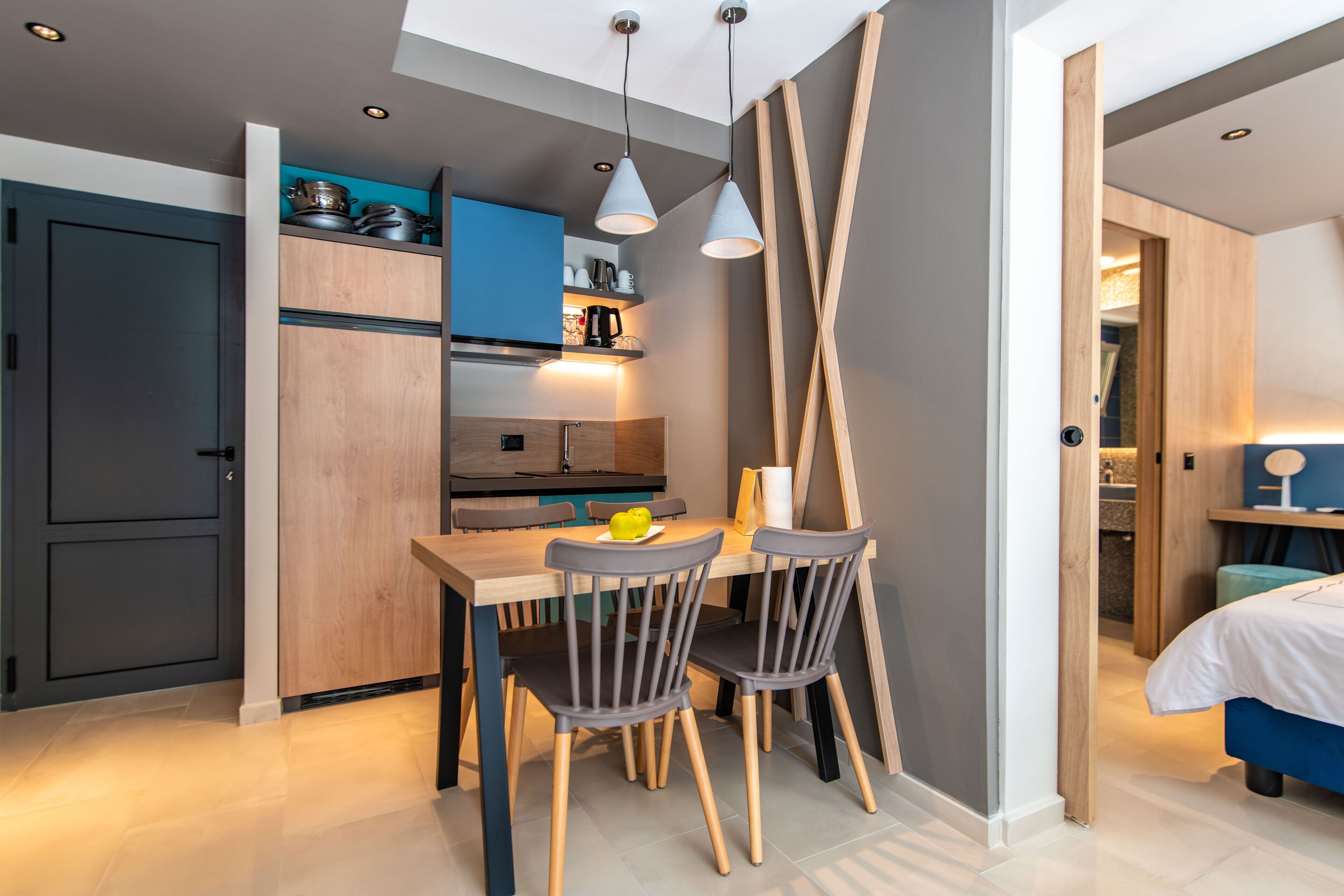 Een compacte keuken met moderne apparatuur, een eethoek met twee stoelen en een zichtbare deuropening naar een slaapkamer.