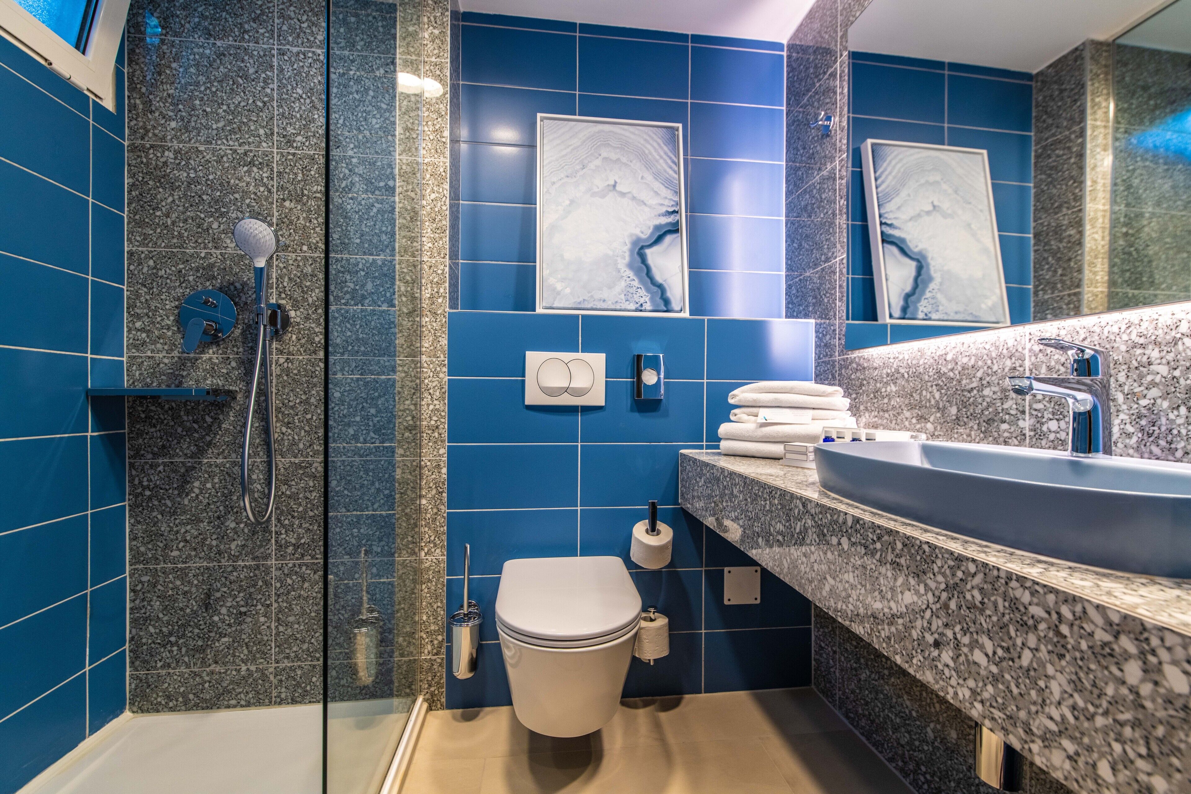 A modern bathroom with a large sink, a toilet, and a shower area.
