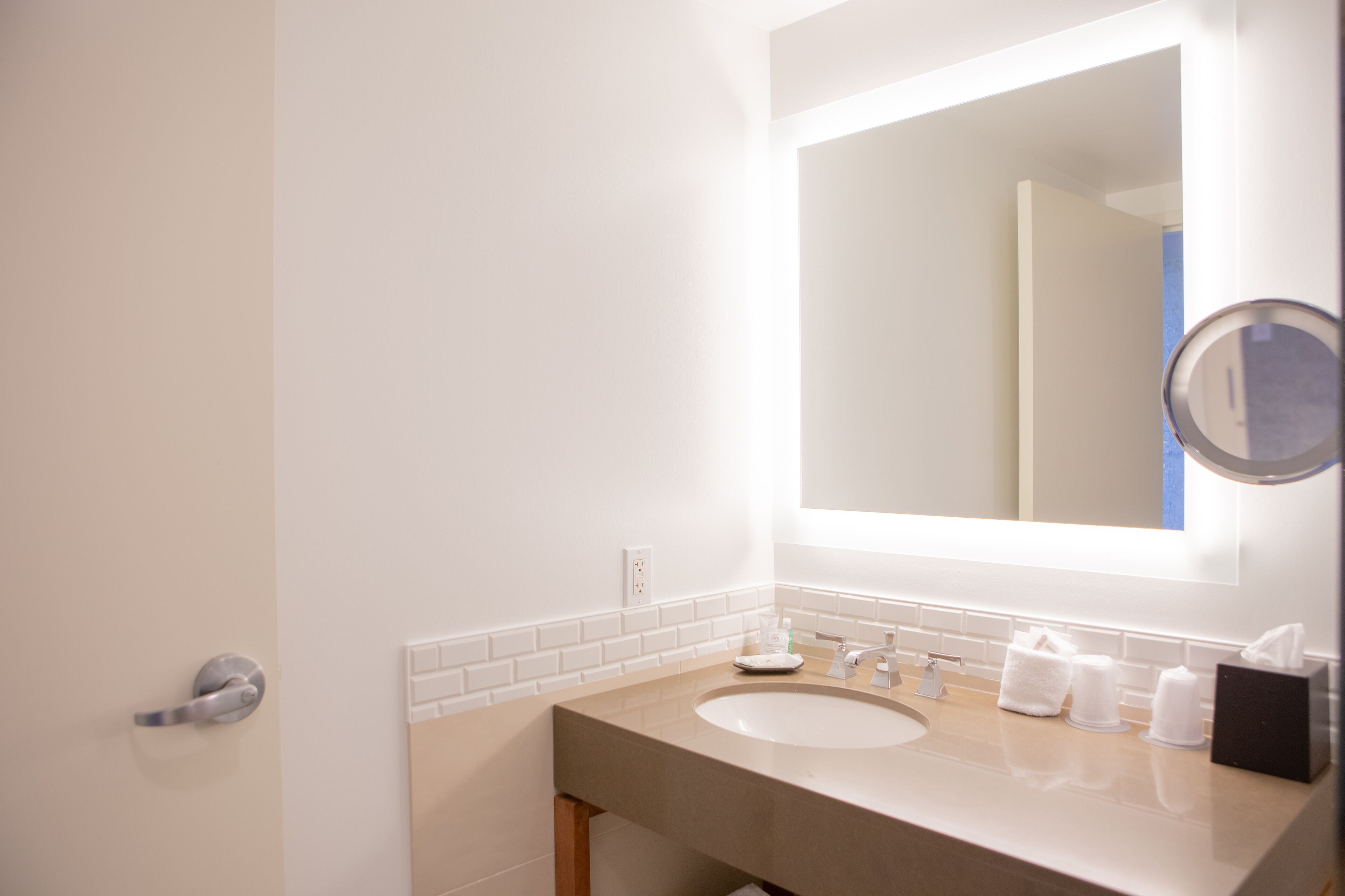 A modern bathroom with a white sink, a mirror, and a towel rack.