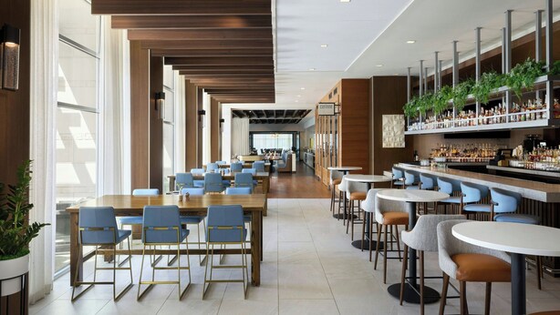 A modern hotel lobby with a long reception desk, multiple seating areas, and a bar with a variety of amenities. - The Westin Austin at The Domain (Austin)