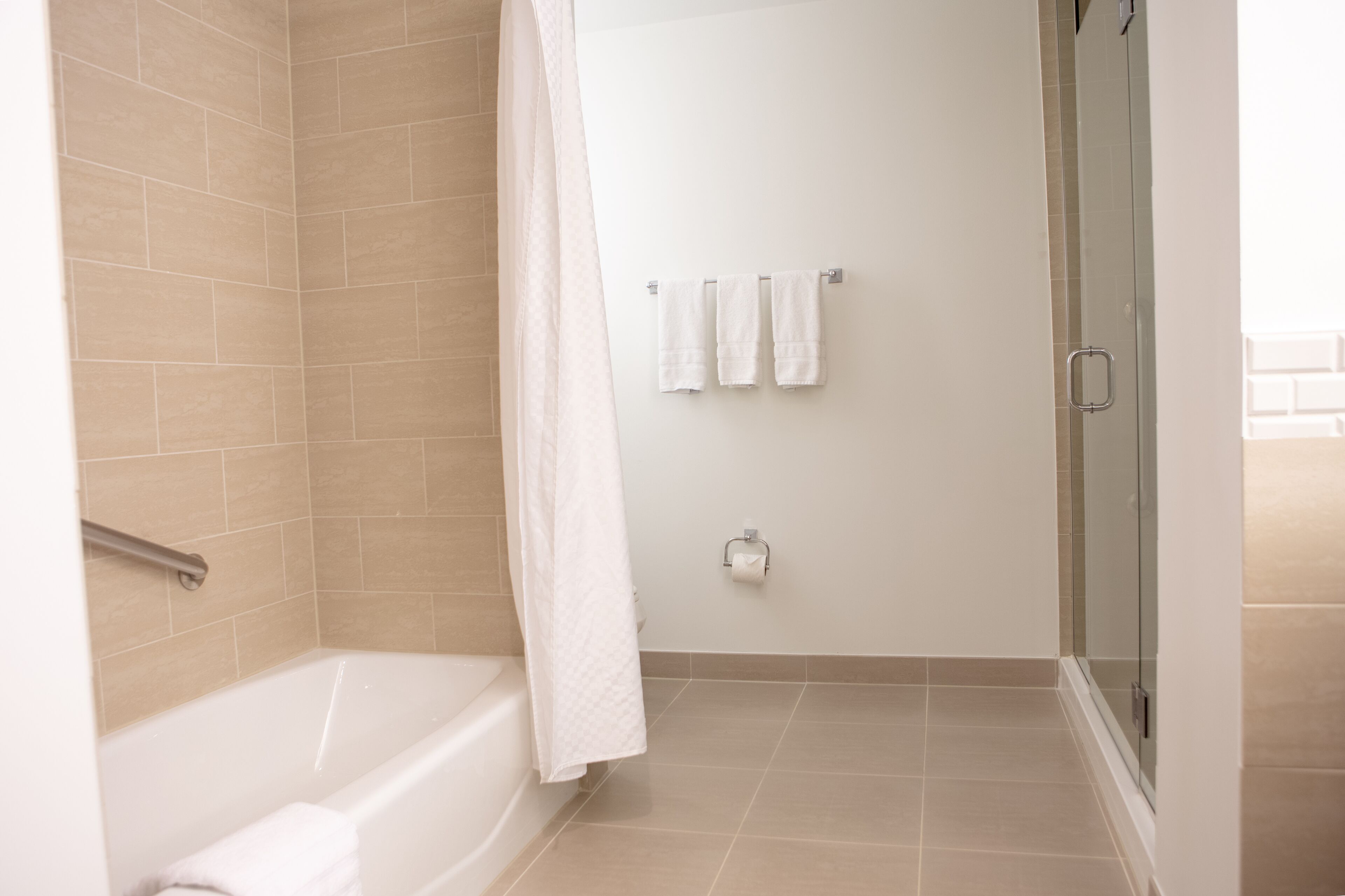 A modern bathroom with a bathtub, shower, and glass-enclosed shower stall.