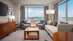 A modern hotel room with a large window, a flat-screen TV, a sofa, a coffee table, and a side table. - The Westin Austin at The Domain (Austin)