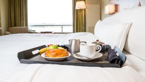 A neatly made breakfast tray on a bed with a view of the sea through a window. - The Westin Austin at The Domain (Austin)