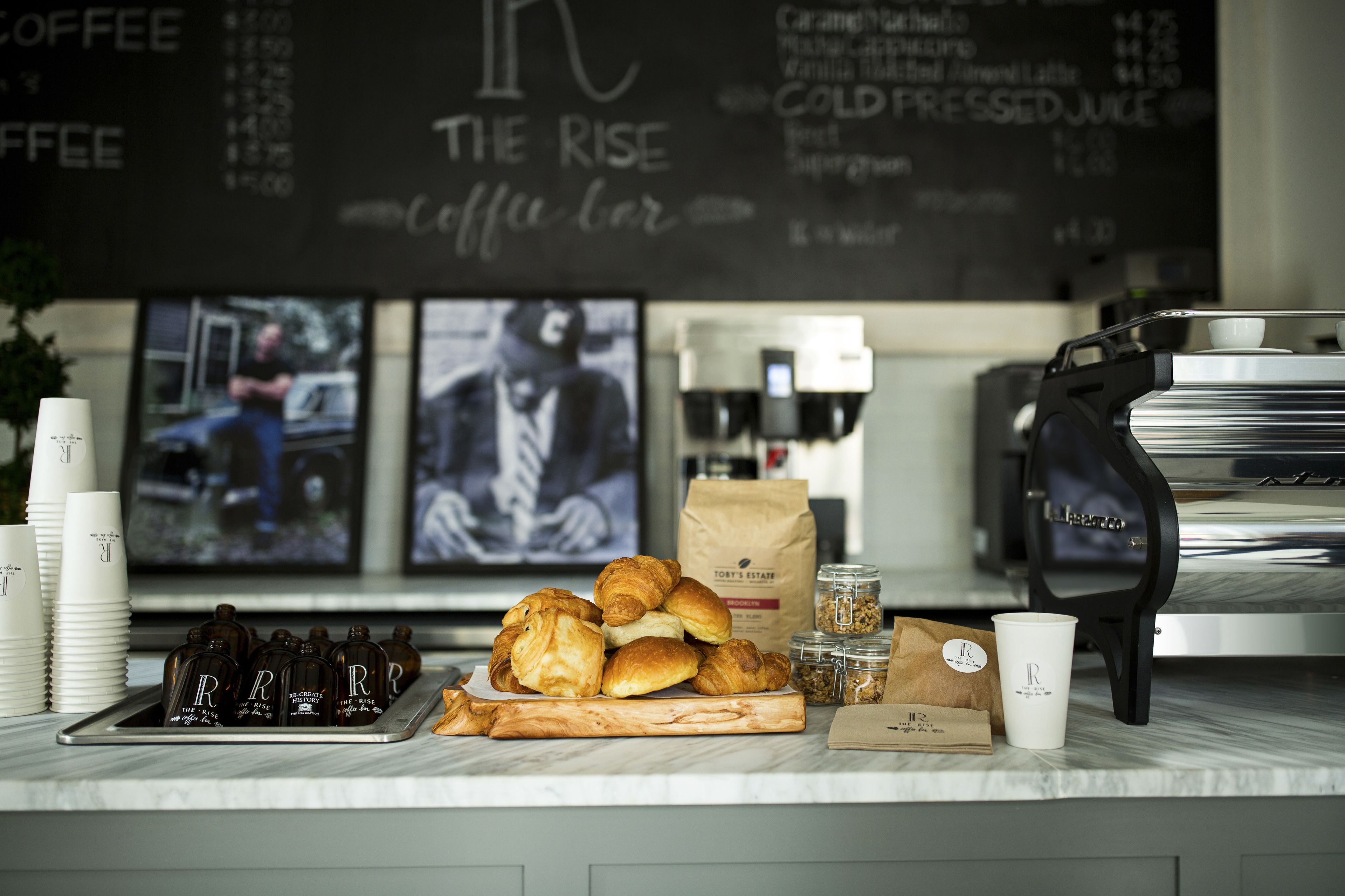 Balcão de café com doces, uma máquina de café e um quadro de cardápio.