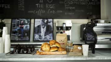 Balcão de café com doces, uma máquina de café e um quadro de cardápio.