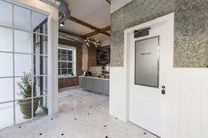 A modern kitchen with a brick wall, a white door labeled "PRIVATE," and a menu board.