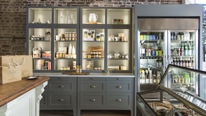 A kitchen with a brick wall, a built-in cabinet with glass doors, and a refrigerator with a glass door.