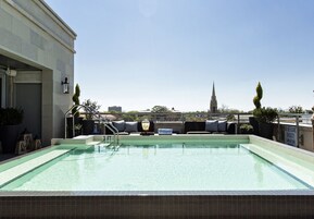 Piscina no terraço com vista para o topo de uma igreja ao longe.