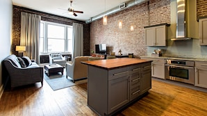 A modern kitchen with a central island, built-in appliances, and a brick accent wall.