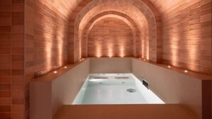 A spa area with a central hot tub, arched brick walls, and recessed lighting. - Hotel du Nord et de l'Est (Paris)