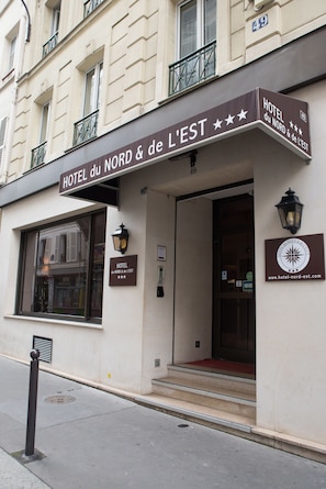 Exterior do HOTEL du NORD & de L'EST, com fachada clássica, entrada destacada com degraus e uma placa com o nome do hotel e site.