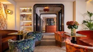 A cozy lounge area with patterned armchairs, a small table, and a decorative mirror. - Hotel du Nord et de l'Est (Paris)