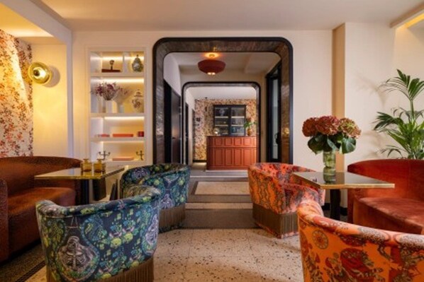 A cozy lounge area with patterned armchairs, a small table, and a decorative mirror.