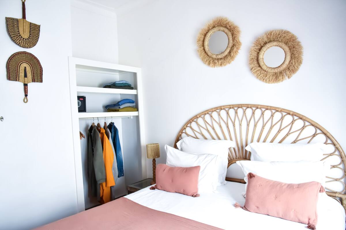 Quarto com uma cama, um guarda-roupa e duas espelhos fixados na parede.