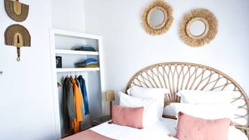 Un dormitorio con una cama, un armario y dos espejos adosados a la pared.
