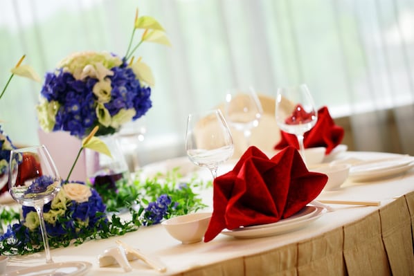 A table set for dining with a vase of flowers, wine glasses, and red napkins. - Dorsett Shanghai (Shanghai)