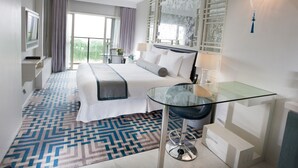 A modern hotel room with a large bed, a glass desk, a chair, a TV, and a balcony with curtains. - Dorsett Shanghai (Shanghai)