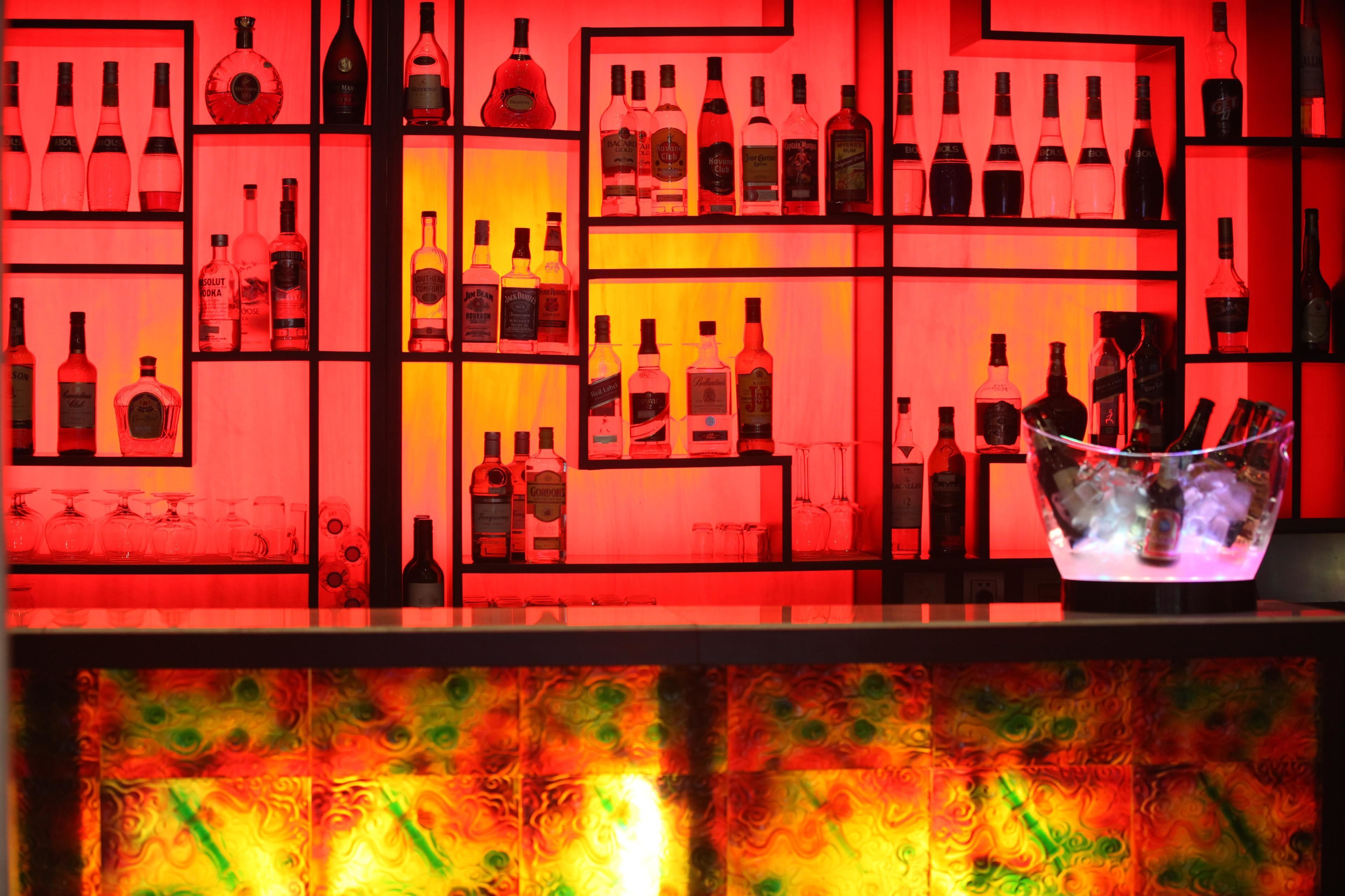 Un espace bar avec des étagères remplies de bouteilles d’alcool et de verres.