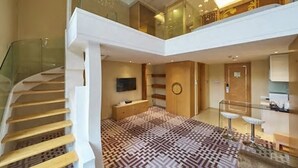 A modern interior with a staircase, a patterned floor, a kitchen area, and a glass railing. - Dorsett Shanghai (Shanghai)