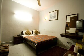 A bedroom with a bed, bedside table, nightstand, TV, and a mirror. - Hotel Woodland Dx (New Delhi)