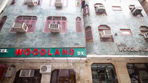 Ein Hotel namens "WOODLAND DX" mit mehreren Klimaanlagen, großen Fenstern und einer Schautafel.