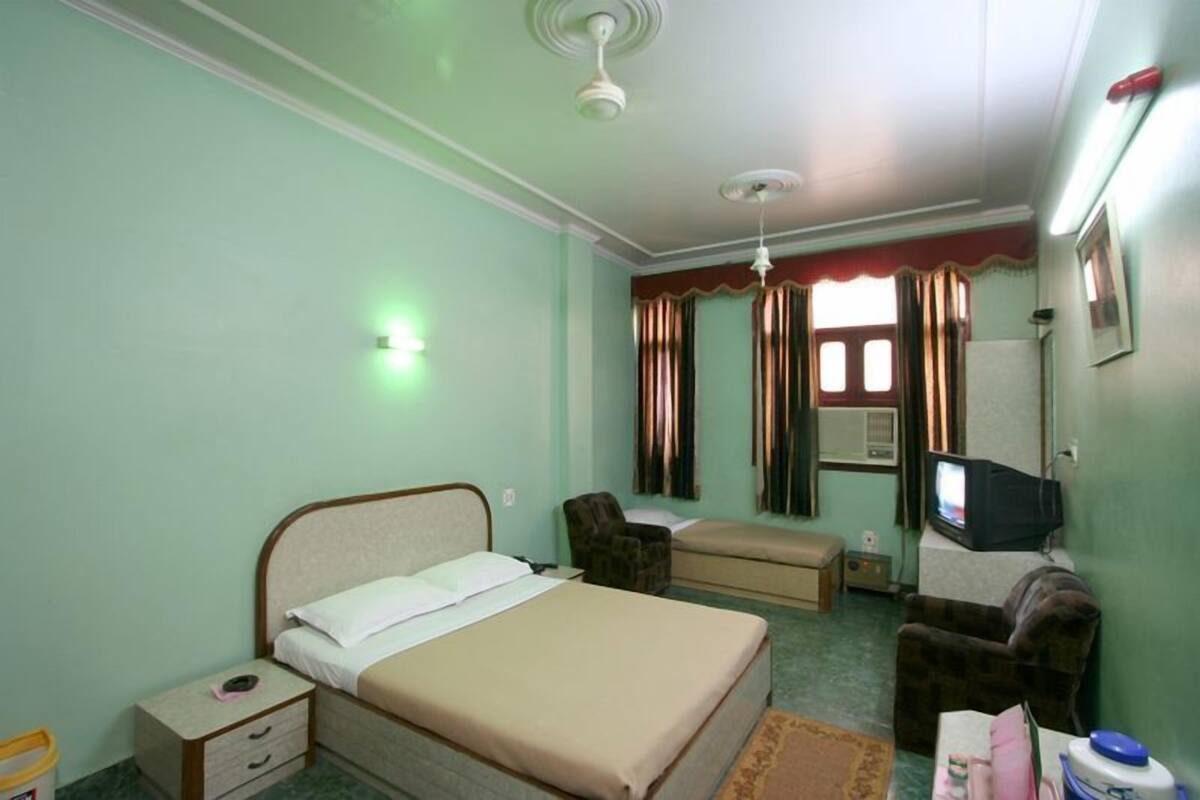 Une chambre à coucher comprenant un lit, une chaise, un canapé, un téléviseur et un radiateur.