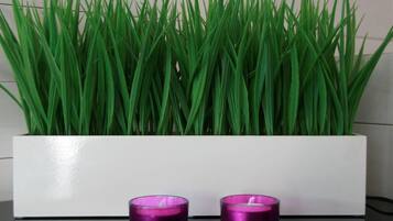A rectangular planter with artificial green grass, two purple candle holders in front.
