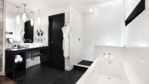 Un bany modern amb una combinació de colors negres i blanques, que inclou una banyera, un lavabo amb mirall i un suport per tovalloles.