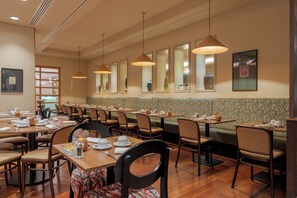 A restaurant with multiple tables and chairs, wooden flooring, and pendant lighting. - Pestana Chelsea Bridge Hotel & SPA (London)