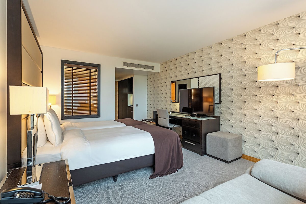 A hotel room with a bed, desk, chair, and a television.