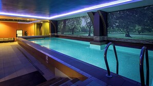 An indoor swimming pool with a view of trees, a sofa, and a staircase. - Pestana Chelsea Bridge Hotel & SPA (London)