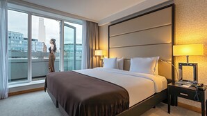 A hotel room with a large bed, two bedside lamps, a nightstand, and a view of a cityscape through a large window. - Pestana Chelsea Bridge Hotel & SPA (London)