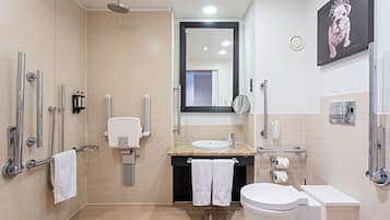 A modern bathroom with a shower, toilet, sink, and handrails.
