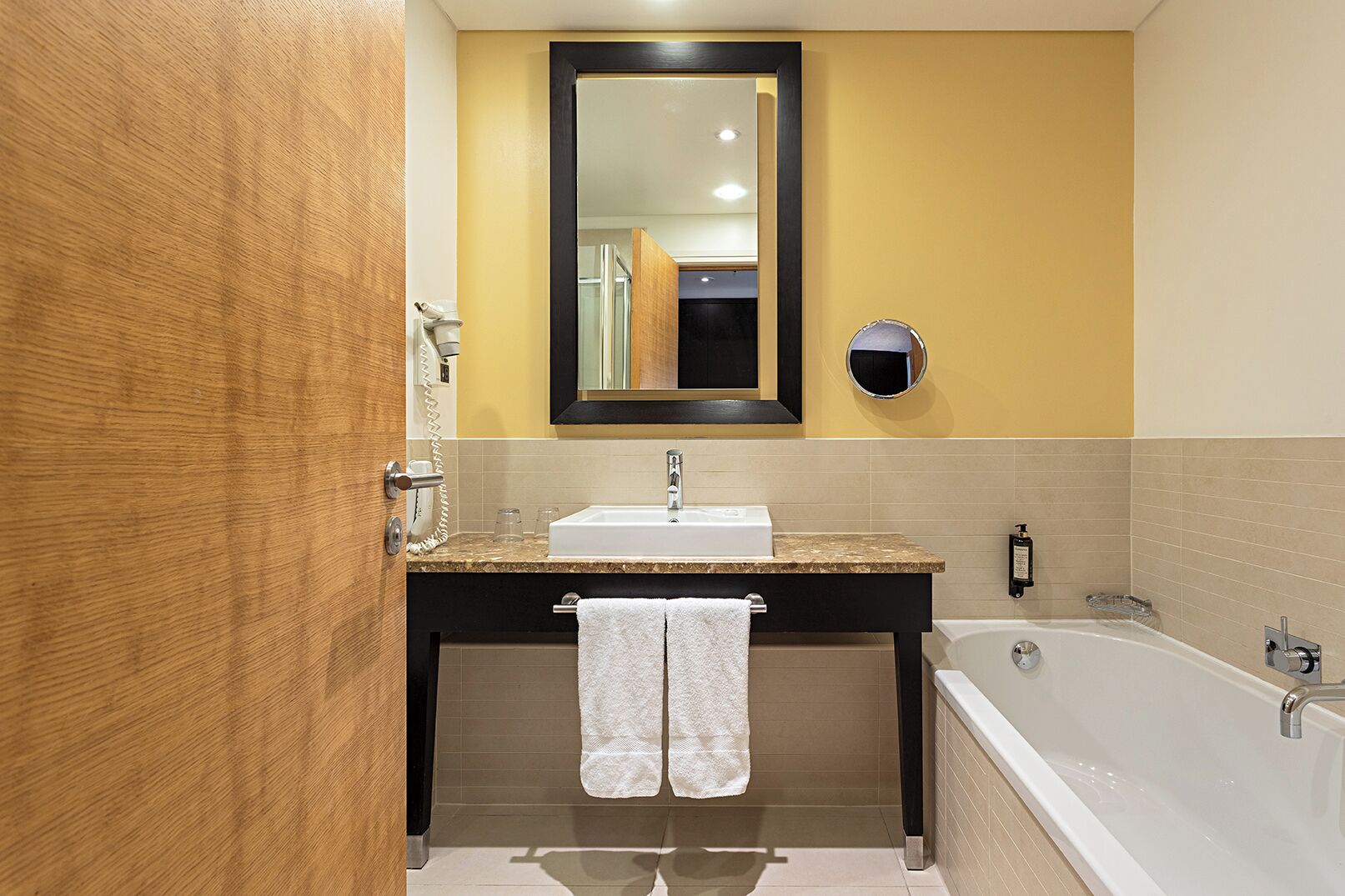 A bathroom with a sink, mirror, towel rack, and bathtub.