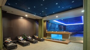 A spa area with lounge chairs, a water feature, and a view of a forest through a glass wall. - Pestana Chelsea Bridge Hotel & SPA (London)
