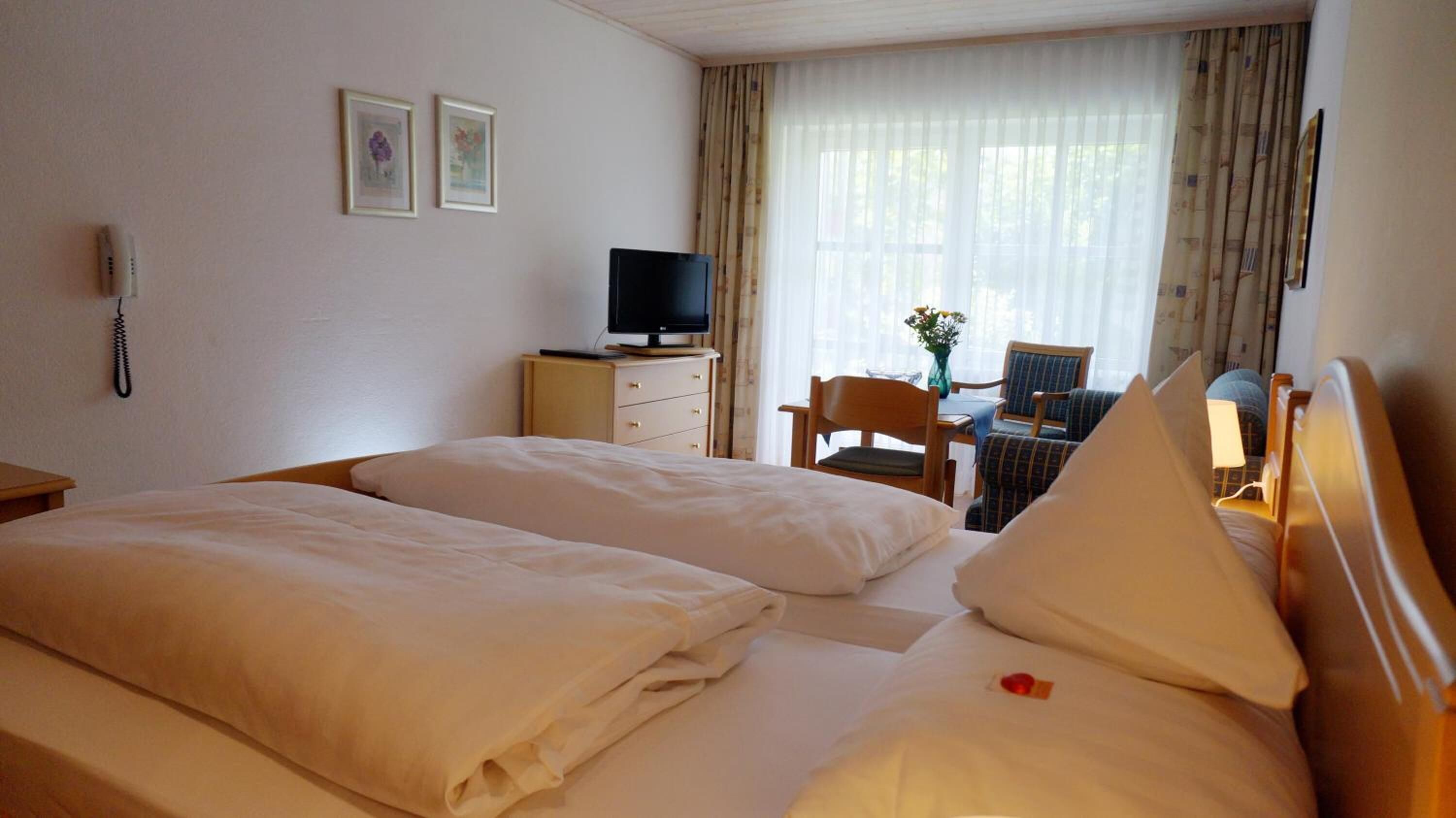 A hotel room with two beds, a desk with a chair, a television, and a phone on the wall.