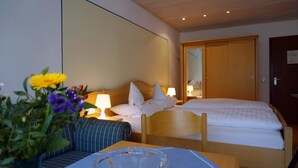 A hotel room with a bed, bedside tables, a mirror, and a wooden wardrobe. - Sonnleiten-Rupert - Aparthotel (Bad Griesbach im Rottal)