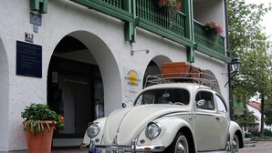 A vintage white car parked in front of a building with green balconies and flower boxes. - Sonnleiten-Rupert - Aparthotel (Bad Griesbach im Rottal)