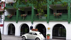 A white vintage car parked in front of a building with green balconies and flower boxes. - Sonnleiten-Rupert - Aparthotel (Bad Griesbach im Rottal)