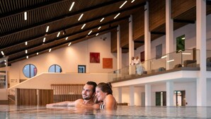 A modern indoor swimming pool with a high ceiling and wooden beams. - Sonnleiten-Rupert - Aparthotel (Bad Griesbach im Rottal)