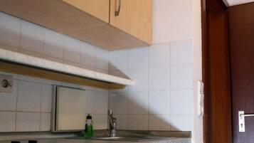Una cocina con armarios de madera, un microondas y un lavamanos de acero inoxidable.