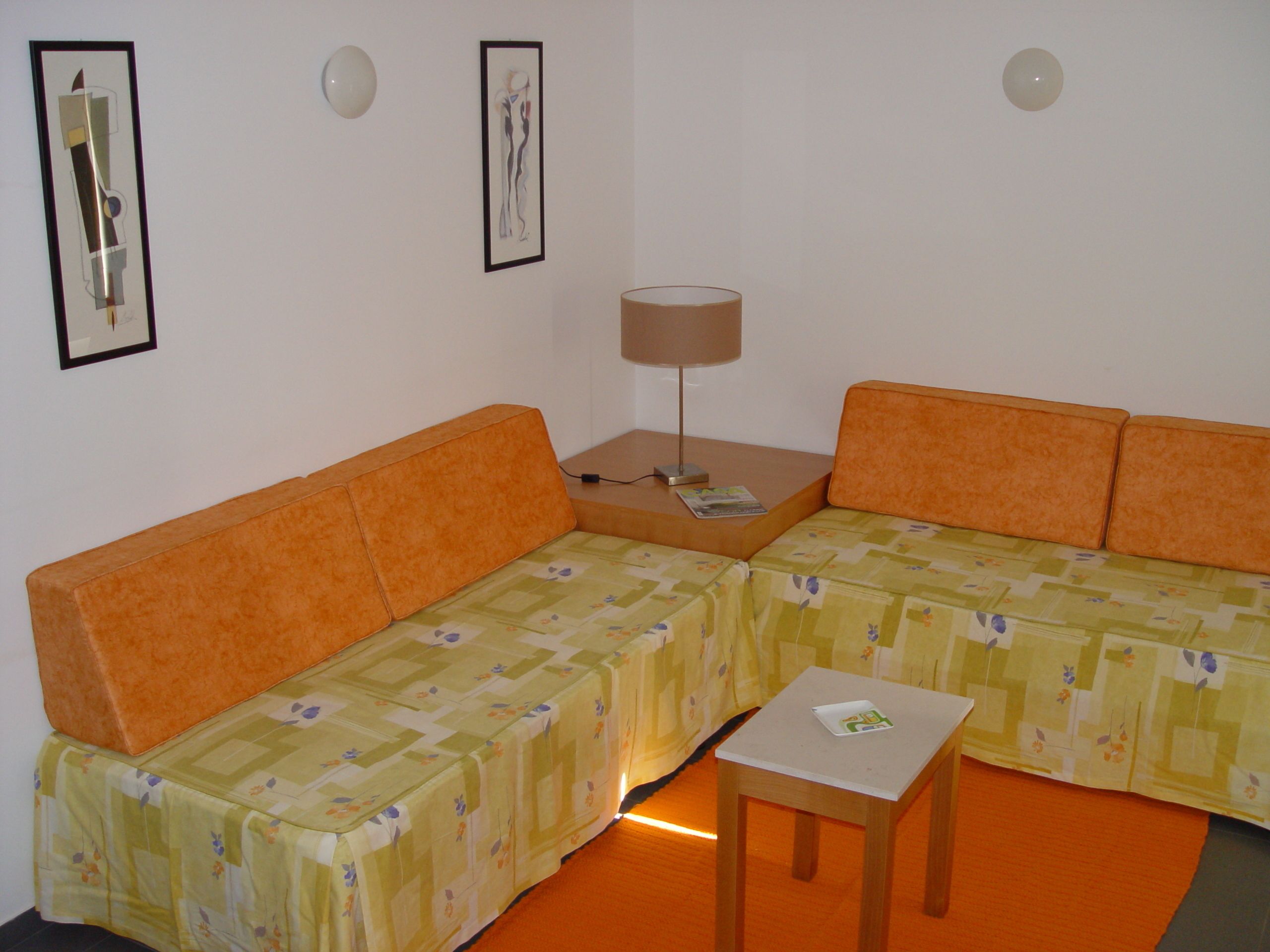 A room with a sofa, a small table, and a lamp.