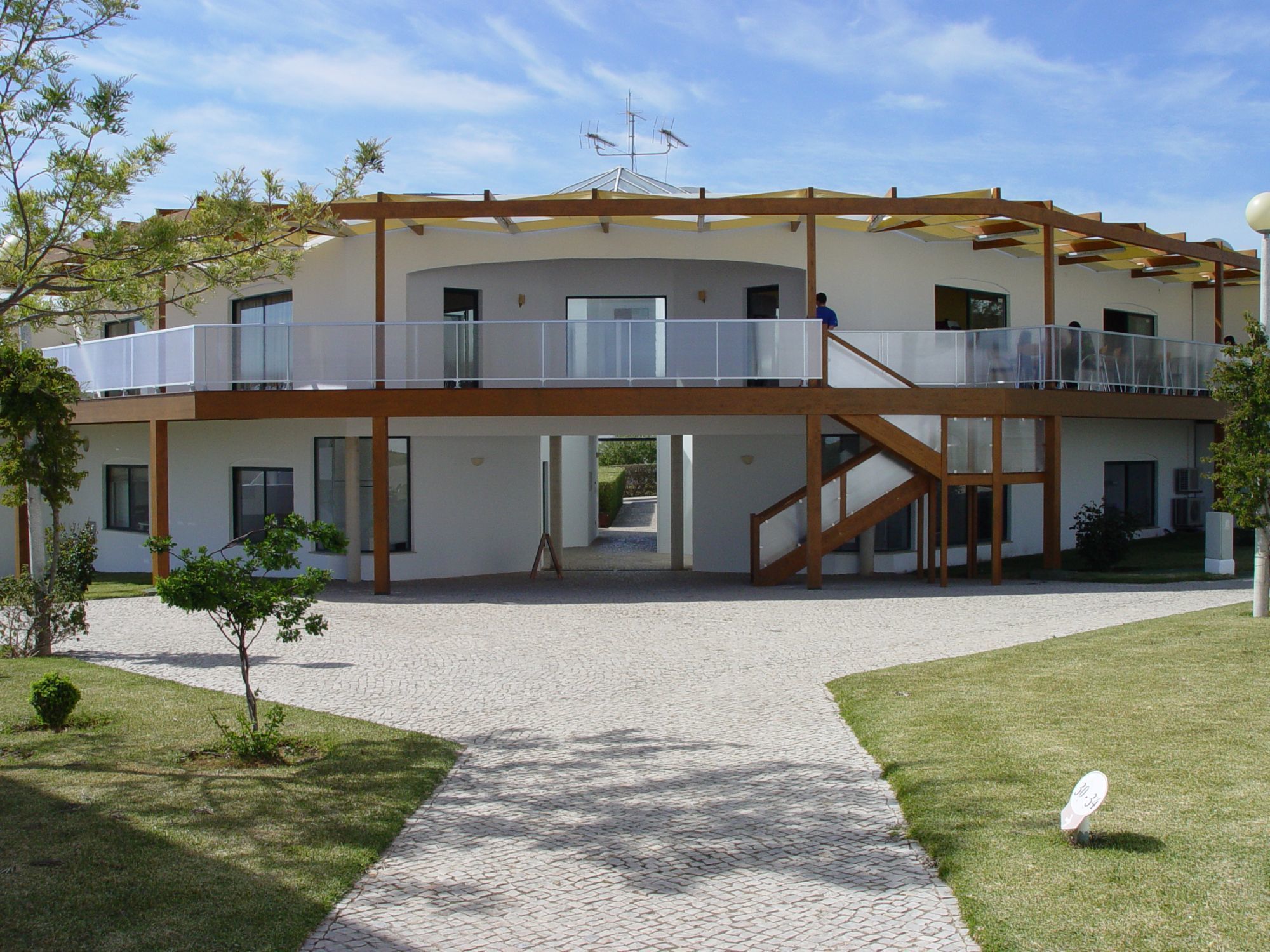 A modern two-story building with a covered outdoor area and a staircase leading to the upper level.
