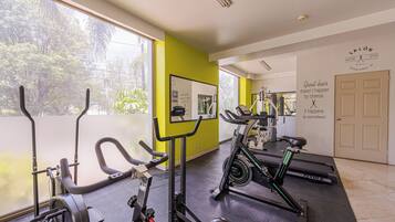 Une salle de sport équipée de matériel d’exercice, d’un tapis de course et d’un miroir.