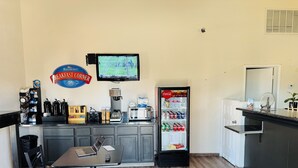 Un comptoir pour prendre le petit-déjeuner, avec une machine à café, un écran de télévision et un réfrigérateur rempli de Coca-Cola.