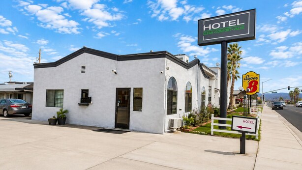 A single-story hotel with a white facade, a black door, and a small porch area.